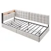 A beige upholstered daybed frame with a metal support structure and a wooden shelf with charging ports. Náhled obrázku produktu