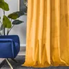 A close-up of a yellow velvet curtain next to a blue armchair and a large potted plant. Produktbild-Vorschau