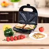 A sandwich maker with sandwiches and vegetables on a wooden table. Náhľad obrázku produktu