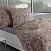 A bed with pillows and a duvet, set against a large window with a view of trees. Produktbild-Vorschau