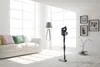 A modern living room with a white sofa, a floor lamp, and a vacuum cleaner. Voir les images du produit