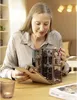 A woman is holding and examining a miniature building model. Produktbild-Vorschau
