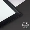 A close-up view of the corner of a black LED panel, showing its textured frame and a white diffuser. The background is split between black and white surfaces, with a circular icon indicating dimmability in the lower right corner. Produktbild-Vorschau