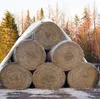 Hay bales stacked under a white tarp in a natural outdoor setting with trees in the background. Náhled obrázku produktu