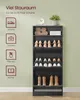 A tall, black shoe cabinet filled with shoes and boots, placed against a light green wall. Icons indicating storage for shoes, bags, plants, and books are on the left side of the image. Produktbild-Vorschau