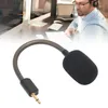 A close-up of a microphone attachment with a blurred background showing a person working at a desk with computers. Voir les images du produit