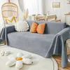 A living room scene with a sofa covered by a gray slipcover, decorated with pillows and a rug. Produktbild-Vorschau