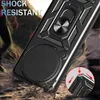 A close-up of a black phone case with a ring stand and camera protection, shown in a dynamic, action-oriented setting with dirt and debris flying. Voir les images du produit