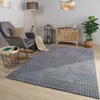 A living room scene with a gray armchair, a floor lamp, a side table, a chest of drawers, a plant, and a rug. Produktbild-Vorschau