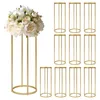 A bouquet of white flowers is displayed on a tall, gold cylindrical stand, with a set of identical gold stands arranged in the background. Podgląd zdjęcia produktu