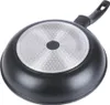 The underside of a black frying pan with a silver, textured base and a black handle, isolated on a white background. Náhled obrázku produktu