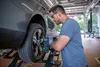 A mechanic is using a cordless impact wrench to remove a lug nut from a car wheel that is elevated on a lift. Voir les images du produit