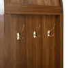 A close-up view of three gold coat hooks mounted on a wooden surface. Anteprima dell’immagine prodotto