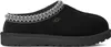 A black UGG slipper shown from the side against a white background. Voir les images du produit
