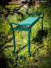 A green garden stool and kneeler sits on the grass in a garden. Produktbild-Vorschau