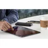 A person is using a tablet while a power bank charges a smartphone and a coffee cup sits nearby. Produktbild-Vorschau