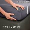 Hands are shown tucking a fitted sheet onto a mattress. Produktbild-Vorschau