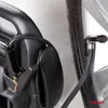 A close-up view of a car tire valve stem connected to a black hose, which is attached to a black car jump starter device. Podgląd zdjęcia produktu