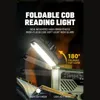 A close-up of a foldable reading light attached to a radio, illuminating a book. Produktbild-Vorschau