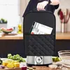 A person is holding a black cover for an ice cream maker, which is placed on a kitchen counter with ingredients. Produktbild-Vorschau
