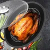 A roasted chicken is presented in an oval roasting pan with a wire rack, alongside some vegetables and spices. Produktbild-Vorschau