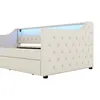 A close-up side view of a cream-colored upholstered bed frame with tufted detailing and integrated LED lighting. Náhled obrázku produktu