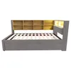 A gray upholstered bed frame with a wooden headboard featuring shelves and integrated lighting, shown from the side. Podgląd zdjęcia produktu