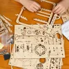 A person's hands are assembling a wooden model kit on a wooden table. Voir les images du produit
