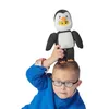 A child wearing glasses and a blue sweater holds a plush penguin toy above their head. Náhled obrázku produktu