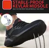 A close-up shot of a person wearing a black safety shoe, demonstrating its puncture-proof sole with metal spikes. Produktbild-Vorschau