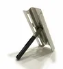 A stainless steel sink overflow cover with a black handle, shown in isolation against a white background. Produktbild-Vorschau