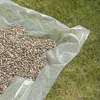 A pile of gravel is spread on a clear plastic sheet laid on grass. Produktbild-Vorschau