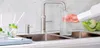 A person is filling a glass flask with water from a Quooker tap in a modern kitchen sink. Anteprima dell’immagine prodotto