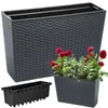 A dark grey rectangular planter with a woven texture, shown with a black plastic insert and a smaller planter with red flowers and green plants. Produktbild-Vorschau
