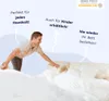 A man is making a bed with white bedding, with text overlays highlighting product features. Produktbild-Vorschau