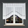 A white lace curtain is shown hanging over a window with a city skyline visible in the background at night. Náhľad obrázku produktu