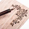 A close-up shot of a wood-burning pen tip on a piece of wood with a floral design. Podgląd zdjęcia produktu
