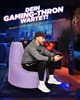 A man is playing a video game while sitting on a large purple beanbag chair in a dimly lit room. Produktbild-Vorschau