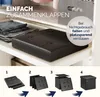 A black storage ottoman is shown folded and placed on a shelf, with a diagram below illustrating the folding process. Produktbild-Vorschau