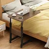 A laptop table is placed next to a bed, with a laptop, a cup of coffee, and a smartphone on it. Produktbild-Vorschau