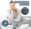 A woman is sitting on a couch holding a gray pillow with a dandelion pattern. There is text and a close-up image of the fabric in the upper right corner, and a 'Made in Europe' logo in the lower left corner. Produktbild-Vorschau