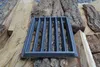 A cast iron grate is placed on top of stacked firewood and bark. Náhled obrázku produktu
