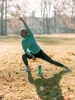 A woman is stretching in a park with a water bottle next to her. Anteprima dell’immagine prodotto