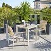 A patio set with a table and chairs on a balcony with plants and a building in the background. Produktbild-Vorschau