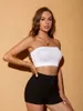 Weißes geripptes Strick-Tube-Top, getragen von einer Frau mit langen braunen Haaren, kombiniert mit schwarzen Shorts Náhľad obrázku produktu