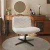 A beige office chair is placed on a round rug in front of a wooden vanity table with a mirror and various decorative items. Produktbild-Vorschau