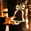 A hand holding a clear bell-shaped LED light decoration with a bow on top, likely for a window. Produktbild-Vorschau