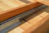 A close-up view of the metal drawer slides and wooden frame of an extendable dining table. Produktbild-Vorschau