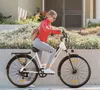 A woman riding an electric bike on a sidewalk next to a garden. Produktbild-Vorschau
