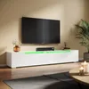 A modern living room with a TV mounted on the wall above a white TV stand with green LED lighting.